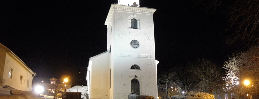 Foto på kvällen i snö där kyrkan är belyst.