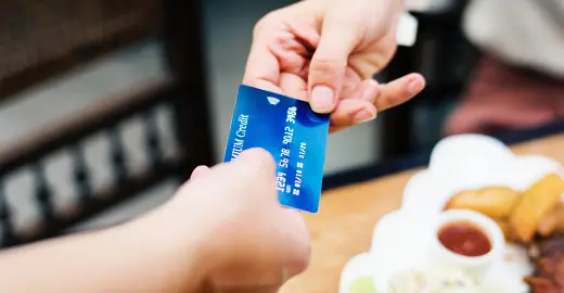 Ett kreditkort som hålls av två händer.