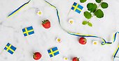 Bild med jordgubbar, svenska flaggan och små vita blommor.